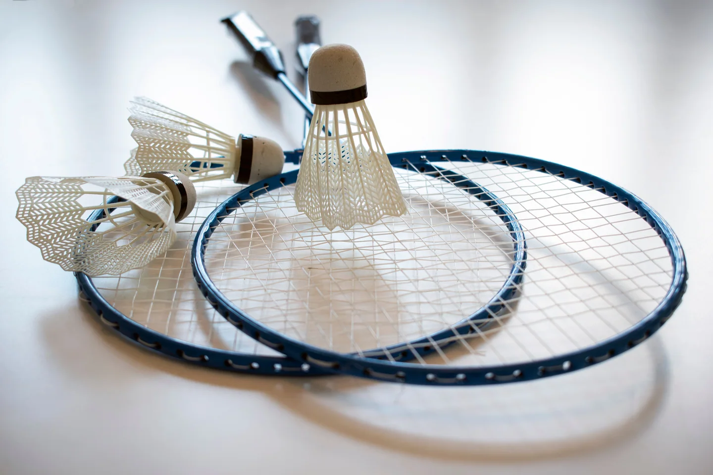 Shuttlecocks resting on the strings of two badminton rackets
