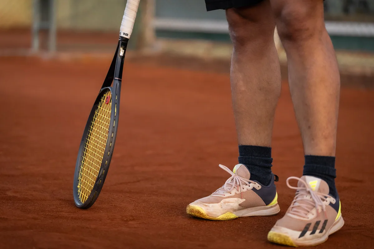 Tennis shoes and racket on a clay court