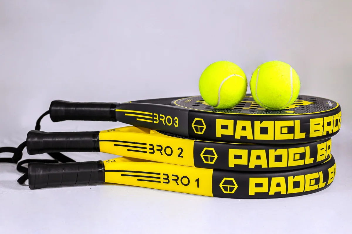 Stacked padel rackets and yellow balls