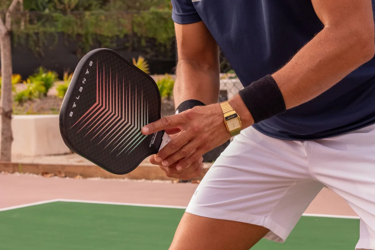 A player holding a solid-faced pickleball paddle on an outdoor court