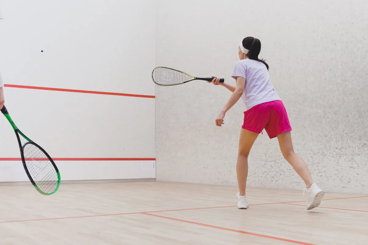 Player striking a ball on an indoor squash court