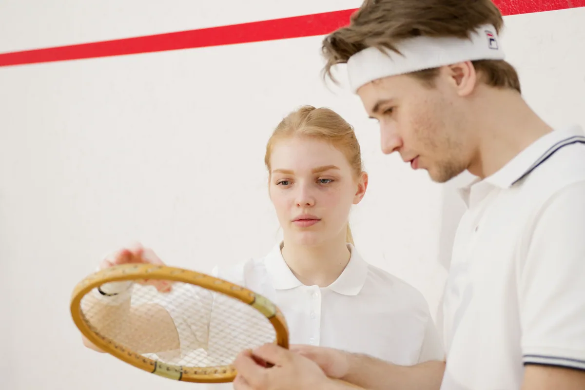 Two squash players examining the strings of a racket