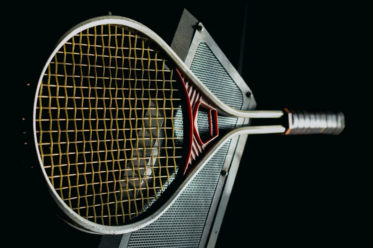 Tennis racket head and strings against a dark background