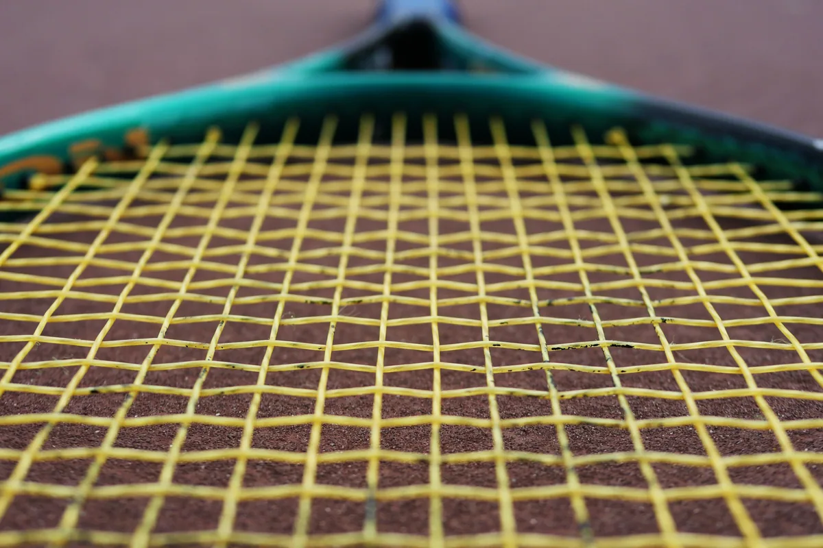 Close-up of yellow strings across a tennis racket